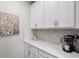 Cozy butler's pantry featuring white cabinets, tile backsplash, quartz counters, and a convenient coffee station at 15316 Shady Palms Ln, Nokomis, FL 34275