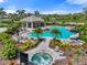 Community pool area with lounge chairs, umbrellas, a spa, and outdoor seating beneath a pergola at 15316 Shady Palms Ln, Nokomis, FL 34275