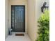 A welcoming front door entrance with modern black hardware, lantern and lush greenery at 15316 Shady Palms Ln, Nokomis, FL 34275