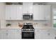 Stylish kitchen features white cabinets, quartz countertops, stainless steel appliances and tile backsplash at 15316 Shady Palms Ln, Nokomis, FL 34275