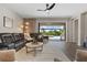 Open living room with a large leather sofa, tile flooring, and access to the outdoor pool and grill area at 15316 Shady Palms Ln, Nokomis, FL 34275