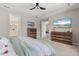 Bright main bedroom showcasing dual dressers, a ceiling fan, and an ensuite bathroom at 15316 Shady Palms Ln, Nokomis, FL 34275