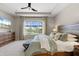 Comfortable main bedroom featuring a tray ceiling, ceiling fan, and scenic views through a large window at 15316 Shady Palms Ln, Nokomis, FL 34275