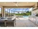 Screened outdoor patio features a built-in grill, fire pit, and spacious seating area overlooking the pool at 15316 Shady Palms Ln, Nokomis, FL 34275