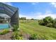 A backyard view showcasing a screened pool enclosure with expansive lawn space and a scenic pond at 15316 Shady Palms Ln, Nokomis, FL 34275