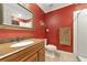 Red bathroom with a granite sink, wood vanity, towel, large mirror, toilet and shower/bath combo at 15440 County Road 675, Parrish, FL 34219