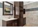 Bathroom featuring a dark-stained vanity, a tall linen cabinet, decorative tiling, and neutral-colored wall tiles at 15440 County Road 675, Parrish, FL 34219