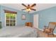 Light blue bedroom with a ceiling fan, rocking chair and large window overlooking a flower garden at 15440 County Road 675, Parrish, FL 34219