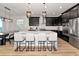 A kitchen featuring a large island with seating, dark cabinetry, stainless steel appliances, and stylish lighting at 17333 Savory Mist Cir, Bradenton, FL 34211