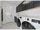 Well-lit laundry room featuring a modern washer and dryer set, along with sleek black cabinets and a convenient sink at 17333 Savory Mist Cir, Bradenton, FL 34211