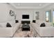 Living room with white sofas, dark furniture, and a large flat-screen TV; view of the outdoor lake at 17333 Savory Mist Cir, Bradenton, FL 34211