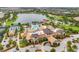 Aerial view of a resort-style clubhouse with pools, tennis courts, and beautifully landscaped grounds next to a lake at 17910 Waterville Pl, Lakewood Ranch, FL 34202