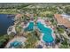 Aerial view of a large community pool surrounded by palm trees, lounge chairs, and a lake at 17910 Waterville Pl, Lakewood Ranch, FL 34202