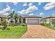 Charming one-story home featuring a well-manicured lawn, beautiful landscaping, and a brick paved driveway at 17910 Waterville Pl, Lakewood Ranch, FL 34202