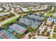 Aerial shot showcasing the community's well-maintained tennis and pickleball courts near a serene lake at 17910 Waterville Pl, Lakewood Ranch, FL 34202