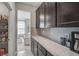 Butler's pantry featuring granite countertop, dark cabinets, grey backsplash and pantry shelves at 2136 Midnight Pearl Dr, Sarasota, FL 34240