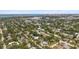 This aerial view overlooks a neighborhood featuring lush tree coverage, the city skyline, and bay waters in the distance at 2275 Clematis St, Sarasota, FL 34239