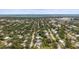 This aerial view shows a neighborhood featuring lush tree coverage, the city skyline, and bay waters in the distance at 2275 Clematis St, Sarasota, FL 34239