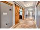 Hallway with eye-catching barn doors, wood-look tile flooring, and elegant tray ceiling at 3218 Big Sky Way, Bradenton, FL 34211