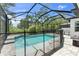 Screened-in pool with an outdoor kitchen, brick pavers, and lush landscaping at 3553 Secluded Ct, Sarasota, FL 34240