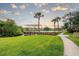 Scenic community view showcasing a wooden dock, palm trees, and waterfront condos against a beautiful sky at 4057 Crockers Lake Blvd # 15, Sarasota, FL 34238