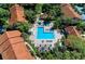 Aerial view of a community pool surrounded by lounge chairs, palm trees, and red-tiled roofed buildings at 4057 Crockers Lake Blvd # 15, Sarasota, FL 34238
