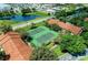 Aerial view of tennis courts near buildings, a pond, and shopping centers in the background at 4057 Crockers Lake Blvd # 15, Sarasota, FL 34238