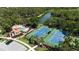 Aerial view of community tennis courts and pool with a covered lounging area next to a lake at 5018 Hanging Moss Ln, Sarasota, FL 34238