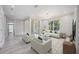 Bright and airy living room with light wood floors, modern furniture, and large windows overlooking lush greenery at 5018 Hanging Moss Ln, Sarasota, FL 34238