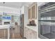 Kitchen with stainless steel appliances and hardwood floors leads to a living room with a fireplace and custom shelving at 510 Wedge Ln, Longboat Key, FL 34228