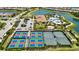 Expansive aerial view featuring colorful tennis courts, a clubhouse, and beautifully landscaped common areas near a serene lake at 5328 Brookgrove Dr, Sarasota, FL 34238