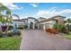 Beautiful home exterior showcasing a three-car garage, and lush landscaping with a paver driveway at 5328 Brookgrove Dr, Sarasota, FL 34238