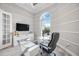 Home office featuring a modern glass desk, ample natural light from a large arched window, and crown molding at 5328 Brookgrove Dr, Sarasota, FL 34238