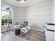 Home office featuring a modern glass desk, ample natural light from a large arched window, and crown molding at 5328 Brookgrove Dr, Sarasota, FL 34238