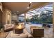 A covered outdoor living space with comfortable seating, a fire pit, grill area and view of a swimming pool with a spa and waterfall at 5328 Brookgrove Dr, Sarasota, FL 34238
