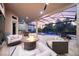 A covered outdoor living space with comfortable seating, a fire pit, grill area and view of a swimming pool with a spa and waterfall at 5328 Brookgrove Dr, Sarasota, FL 34238
