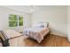 Bright bedroom featuring wood floors, ceiling fan, and a window with a lush green view at 5500 Longwood Run Blvd # 203, Sarasota, FL 34243