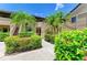 Inviting condo building with tropical landscaping, including palm trees and colorful flowering bushes at 5728 Ashton Lake Dr # 12, Sarasota, FL 34231