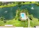 Aerial view of a tranquil community pool surrounded by palm trees and overlooking a serene lake at 5728 Ashton Lake Dr # 12, Sarasota, FL 34231
