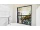 Bright bathroom featuring modern fixtures, soaking tub, and serene garden view from a large picture window at 6107 Misty Oaks St, Sarasota, FL 34243