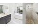 Bathroom with dual sink vanity, soaking tub, glass enclosed shower, and pebble tile shower floor at 6107 Misty Oaks St, Sarasota, FL 34243