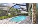 A swimming pool with an enclosure and brick columns that support the roof with lush landscaping in the background at 6107 Misty Oaks St, Sarasota, FL 34243