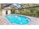 A beautiful screened-in pool features tiled brick patio, mature landscaping, and clear blue water at 6107 Misty Oaks St, Sarasota, FL 34243