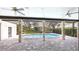 Covered patio featuring ceiling fans, stone pillars, and a private pool with lush landscaping in the background at 6107 Misty Oaks St, Sarasota, FL 34243