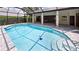 A swimming pool with an enclosure and brick columns that support the roof with lush landscaping in the background at 6107 Misty Oaks St, Sarasota, FL 34243
