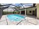 A swimming pool with an enclosure and brick columns that support the roof with lush landscaping in the background at 6107 Misty Oaks St, Sarasota, FL 34243