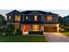 Inviting two-story home featuring a well-maintained lawn and a two-car garage, illuminated by warm exterior lighting at 6302 Anise Dr, Sarasota, FL 34238