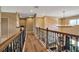Upstairs hallway featuring wood floors, rod iron railing, and stone accent wall at 6302 Anise Dr, Sarasota, FL 34238