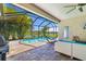 Screened-in pool area featuring a BBQ grill, comfortable seating, a pool with a hammock, and a view of the lake at 650 Rosemary Cir, Bradenton, FL 34212