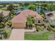 Beautiful tan home with a red tile roof, paver driveway, two car garage and lush landscaping on a lake at 673 Crane Prairie Way, Osprey, FL 34229